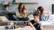 Three teenagers sitting on a couch while using their mobile phones to surf on the internet.